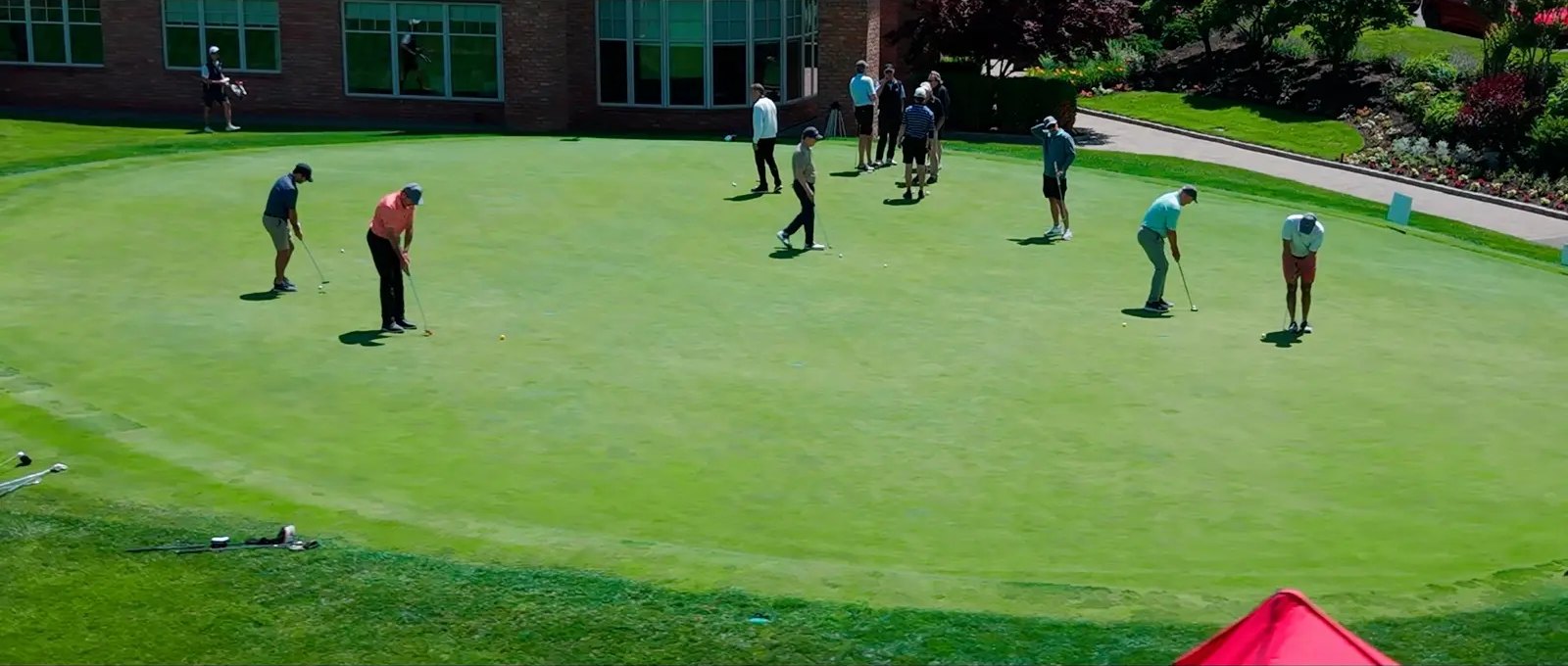 Golfers on a putting green in the sun at a charity golf classic.