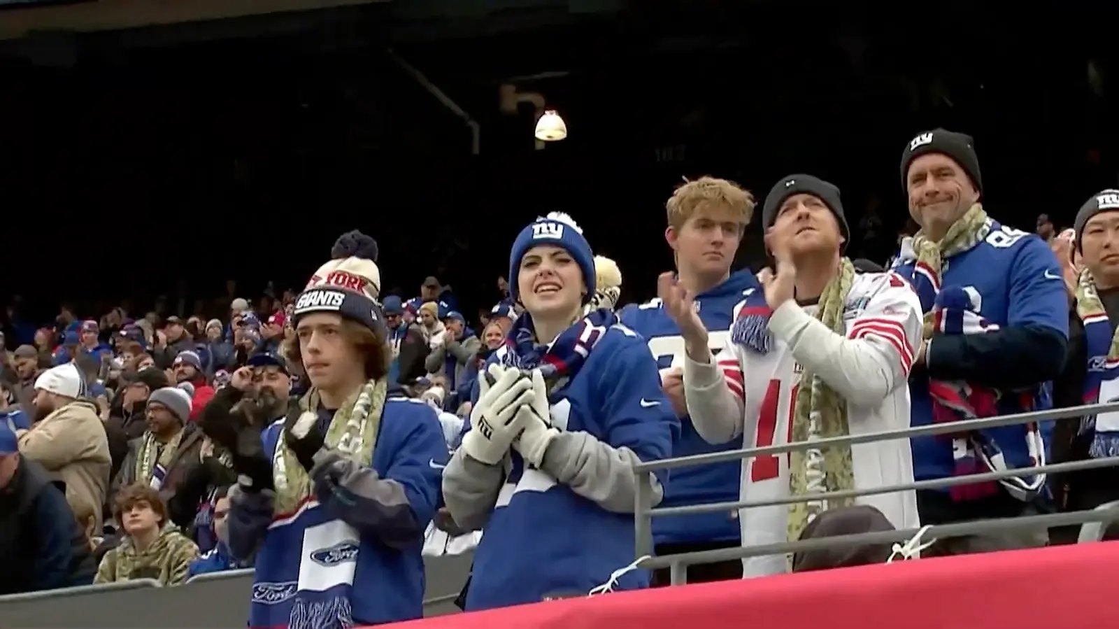 Fans in a stadium standing and applauding.