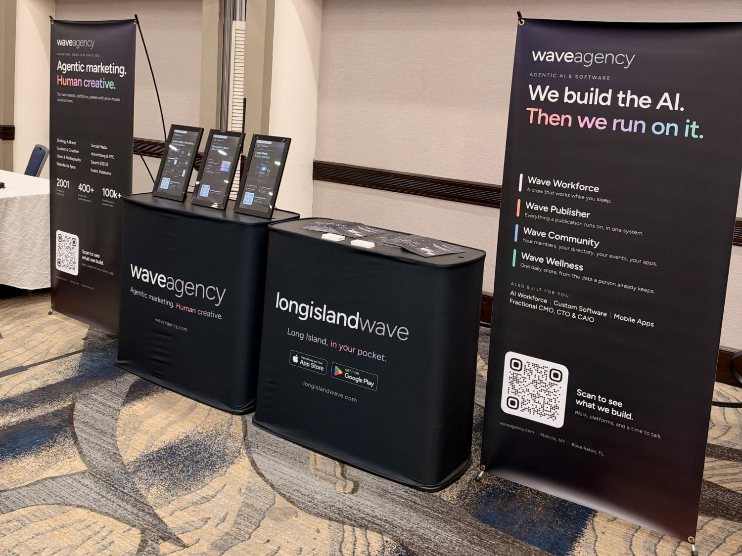 A Wave Agency banner reading We build the AI. Then we run on it., listing Wave Workforce, Wave Publisher, Wave Community and Wave Wellness, beside the Long Island Wave table with App Store and Google Play badges.