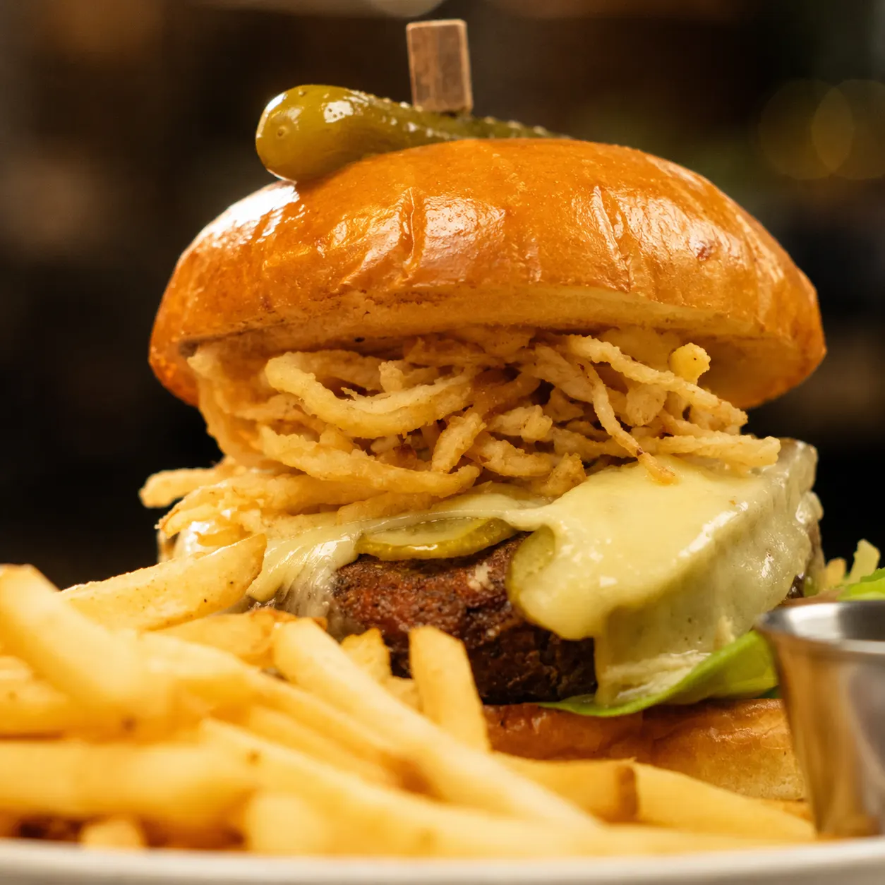 A burger stacked with crispy onions beside a pile of fries.