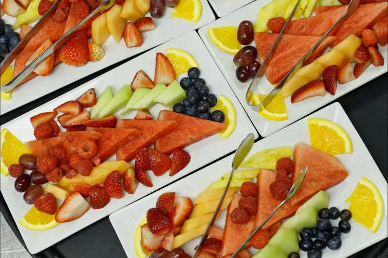 Platters of sliced melon, berries and citrus fanned out for a buffet.