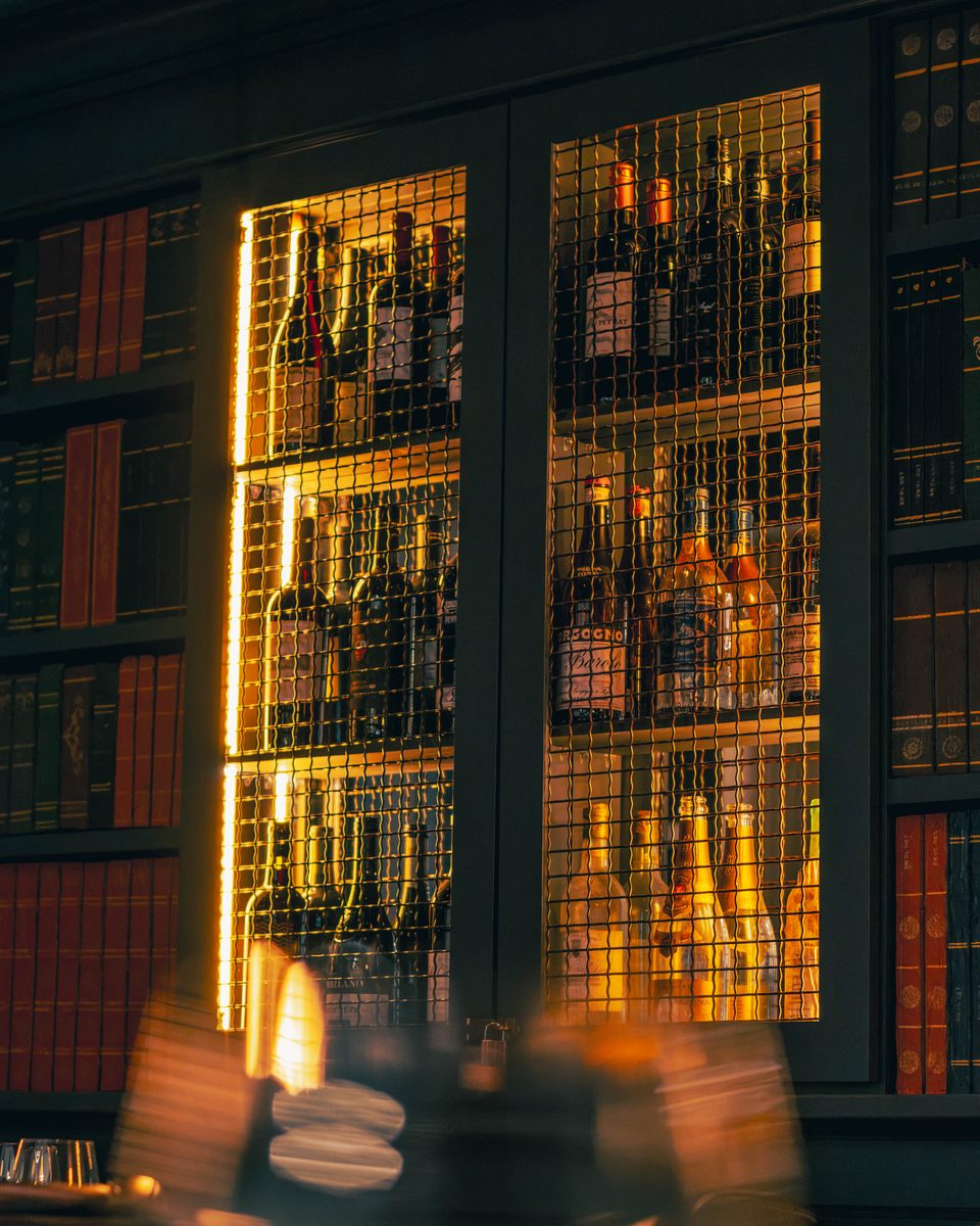 The lit bottle wall, every shelf glowing through the glass.