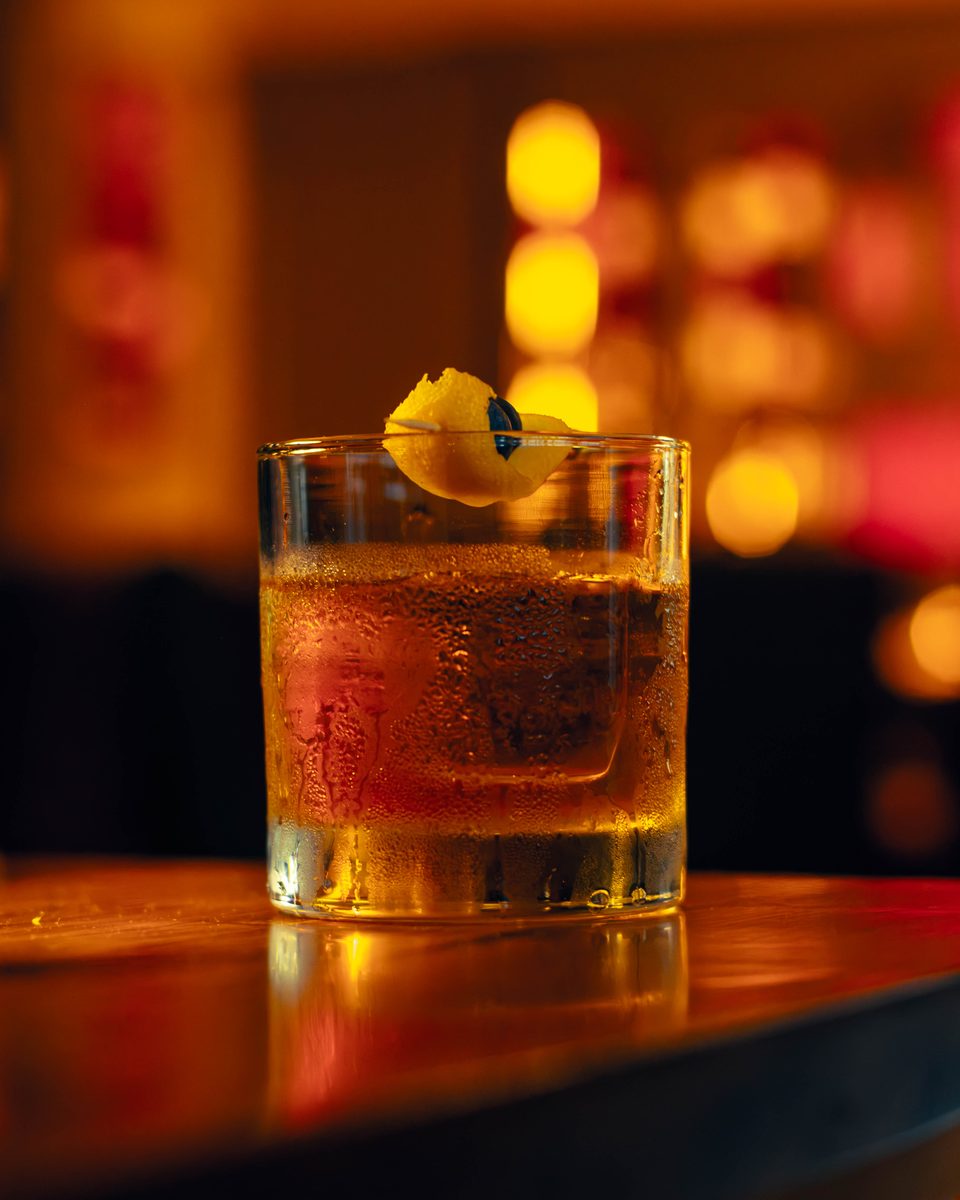 An old fashioned on the bar, the lights behind it thrown out of focus.